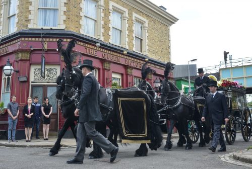 WARNING: Embargoed for publication until 00:00:01 on 28/06/2016 - Programme Name: EastEnders - July - September 2016 - TX: 04/07/2016 - Episode: EastEnders July - September 2016 - 5310 (No. n/a) - Picture Shows: *STRICTLY NOT FOR PUBLICATION UNTIL 00:01HRS, TUESDAY 28th JUNE, 2016* The Carters show their respects as Peggy's funeral procession pulls into Albert Square. Johnny Carter (TED REILLY), Linda Carter (KELLIE BRIGHT), Lee Carter (DANNY-BOY HATCHARD), Whitney Dean (SHONA MCGARTY) - (C) BBC - Photographer: Jack Barnes